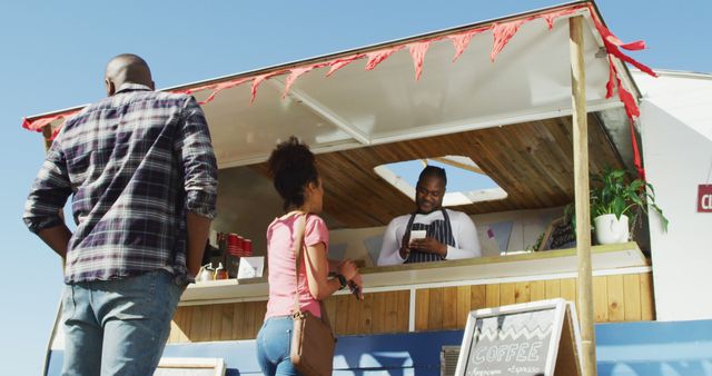 African american man wearing apron taking order from a woman at the food truck. food truck and street food concept