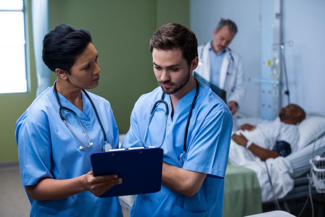 Male and female nurse having discussion over clipboard in ward - Download Free Stock Photos Pikwizard.com
