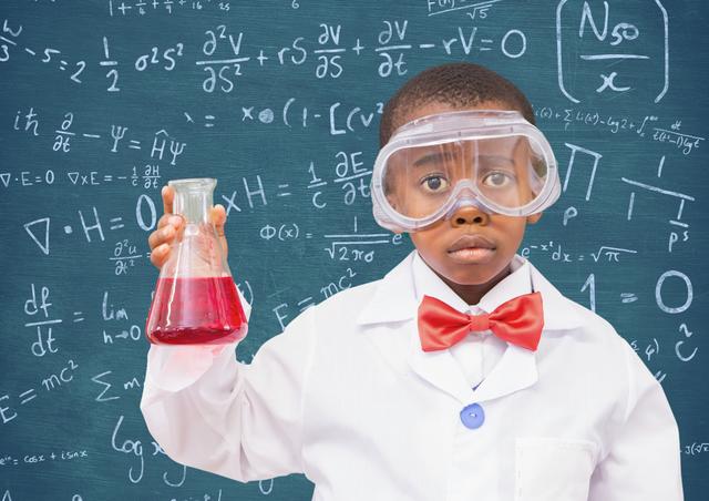 Portrait of boy wearing protective glasses holding a beaker against black board
