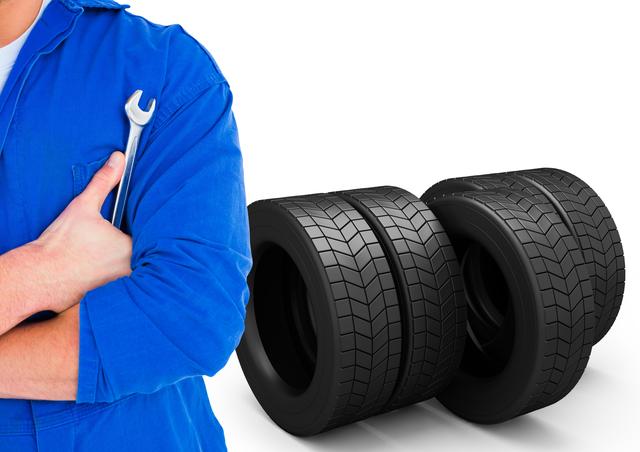 Mid section of mechanic holding a wrench against tires in background - Download Free Stock Photos Pikwizard.com
