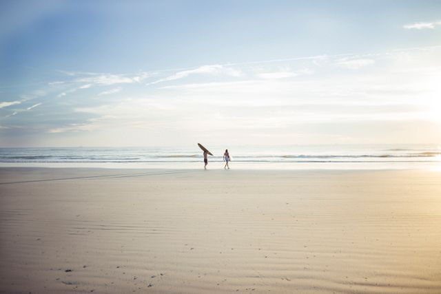 Two people with surfboards walking on the beach. summer vacation and holiday concept