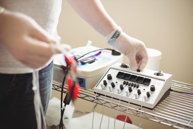 Mid section of a physiotherapist adjusting the electro dry needling unit in clinic