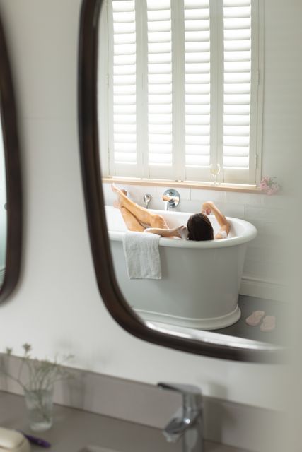Reflection of woman in mirror taking bath in bathtub - Download Free Stock Photos Pikwizard.com