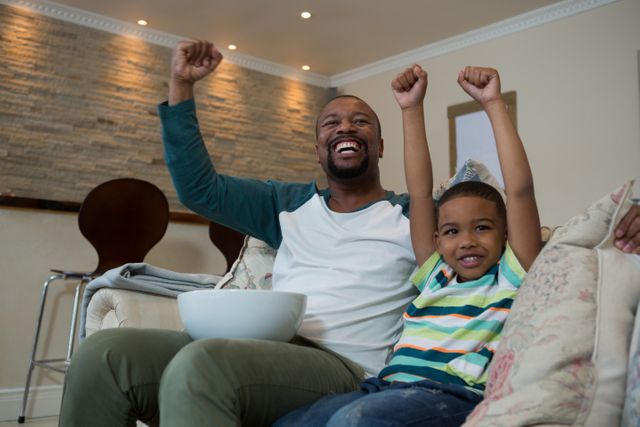 Excited father and son watching football match in living room  - Download Free Stock Photos Pikwizard.com