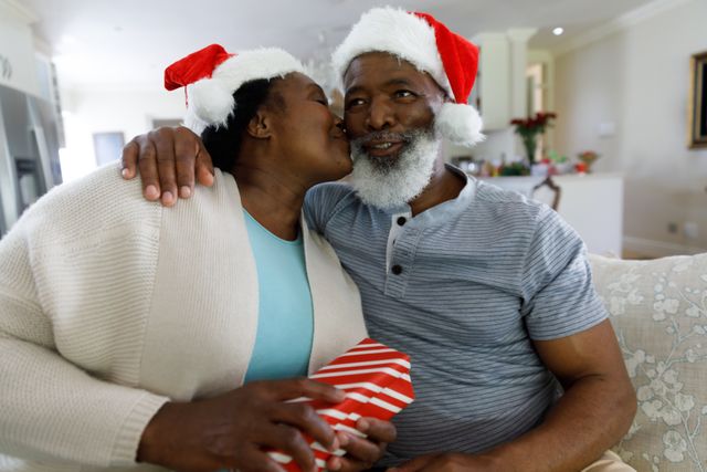 Front view of an old african-american couple sitting on the couch with the woman about to kiss her h - Download Free Stock Photos Pikwizard.com