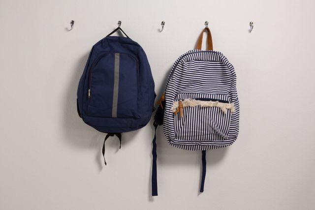 Schoolbags hanging on hook against wall
