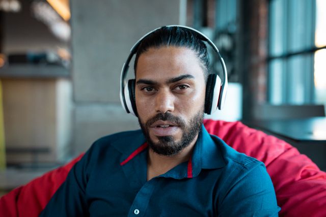 Portrait of handsome mixed race man sitting in cafe wearing wireless headphones - Download Free Stock Photos Pikwizard.com