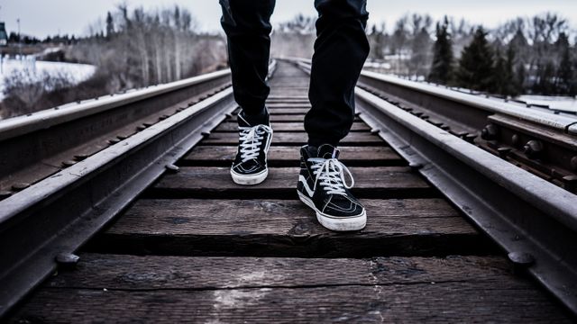Person in Black Pants With Black Vans High Top Sneakers Standing on Railroad Tracks during Daytime - Download Free Stock Photos Pikwizard.com