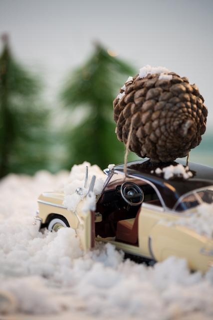 Toy car carrying pine cone on fake snow - Download Free Stock Photos Pikwizard.com