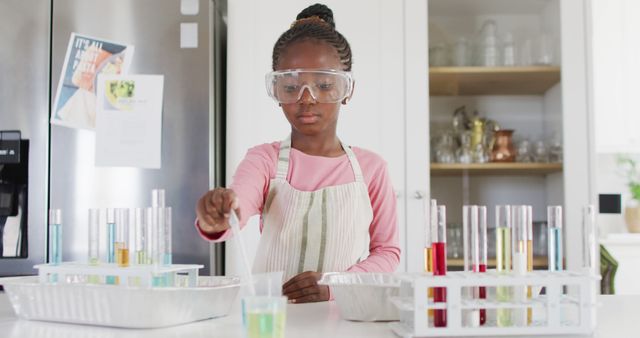Serious african american girl in safety glasses doing chemistry experiment at home, with copy space. Science, education, learning and domestic life.
