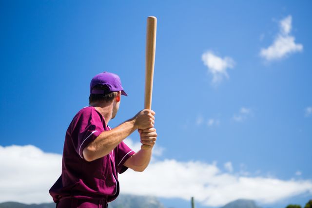 Low angle view of baseball player holding bat against blue sky - Download Free Stock Photos Pikwizard.com