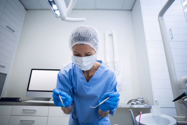 Dental assistant in surgical mask holding dental tools - Download Free Stock Photos Pikwizard.com