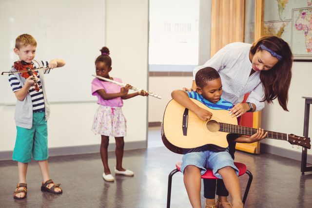 Teacher assisting a kids to play a musical instrument in classroom - Download Free Stock Photos Pikwizard.com