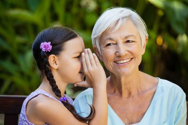 Granddaughter whispering in ears of smiling grandmother - Download Free Stock Photos Pikwizard.com