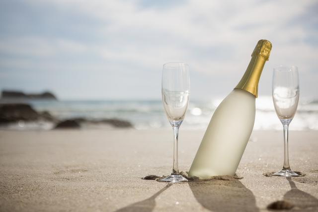 Champagne bottle and two glasses on sand - Download Free Stock Photos Pikwizard.com