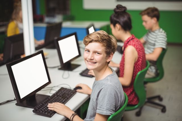 Portrait of smiling schoolboy studying in computer classroom - Download Free Stock Photos Pikwizard.com
