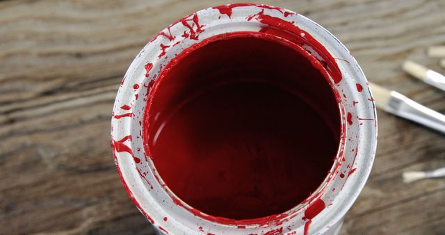 Close up of red paint can and brushes on wooden background