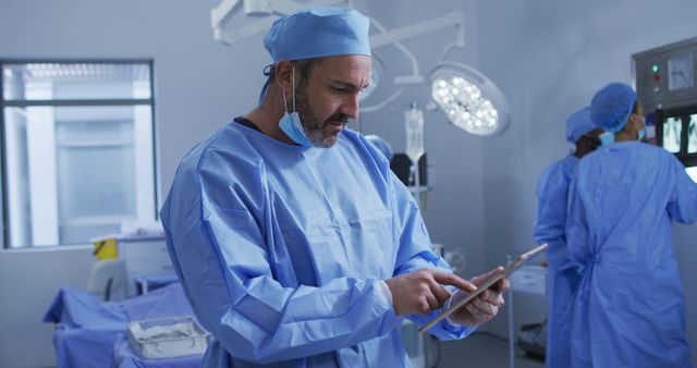 Portrait of caucasian male surgeon standing in operating theatre using tablet. medicine, health and healthcare services.