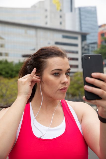 Woman putting earphones while using smartphone - Download Free Stock Photos Pikwizard.com