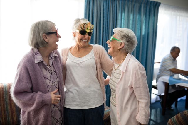 Senior female friends wearing novelty glasses talking at nursing home - Download Free Stock Photos Pikwizard.com