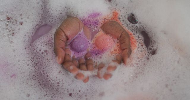 Hands of african american attractive woman taking bath with foam, salt and rose petals. beauty, pampering, home spa and wellbeing concept.