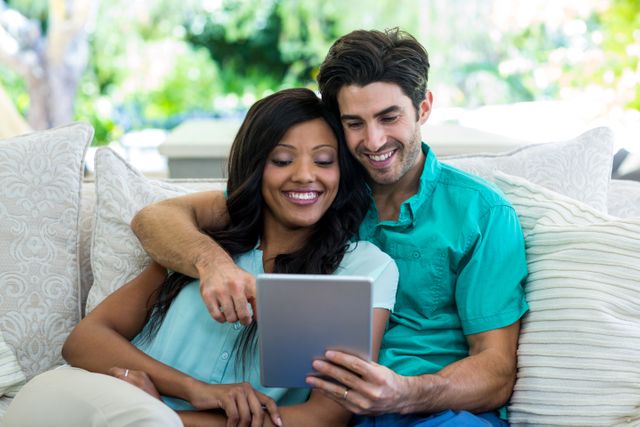 Young couple sitting on sofa and using digital tablet at home