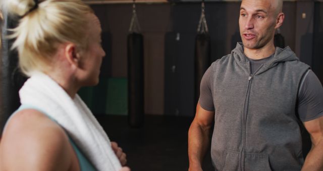 Caucasian male trainer talking to fit caucasian woman at the gym. sports, training and fitness concept