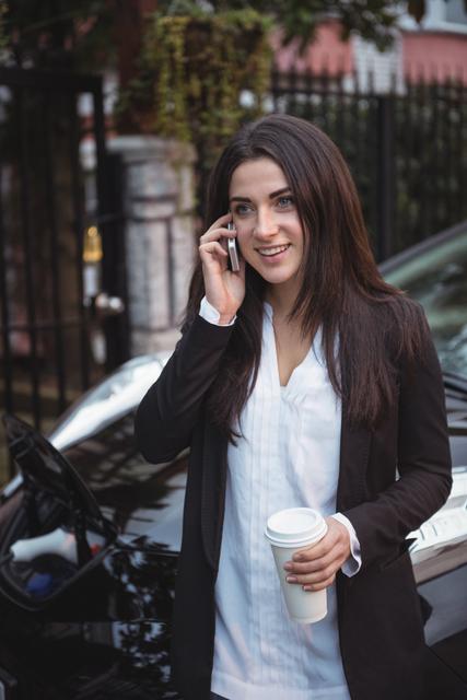 Woman talking on mobile phone while car being charged in background - Download Free Stock Photos Pikwizard.com