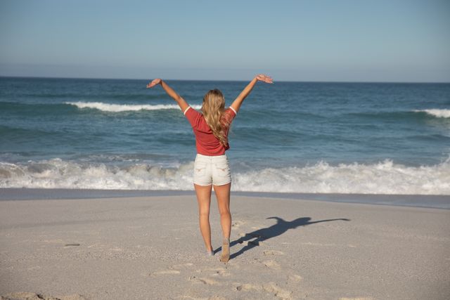 Rear view of woman with her arms wide open at the beach - Download Free Stock Photos Pikwizard.com