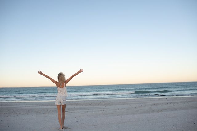 Woman standing with arms outstretched on the beach  - Download Free Stock Photos Pikwizard.com