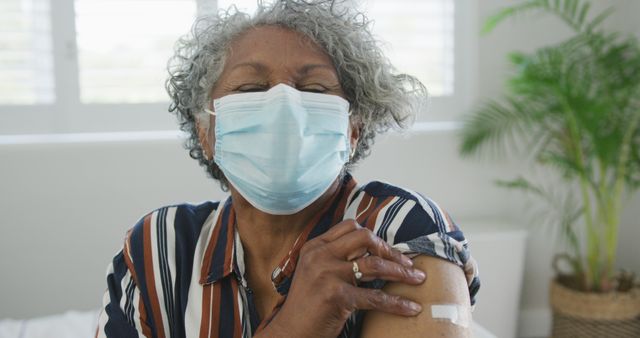 African american senior woman wearing face mask with plaster after vaccination. senior health and lifestyle during covid 19 pandemic.
