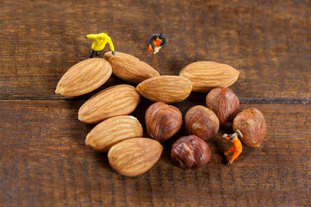 Conceptual image of miniature workers working with almonds and nuts