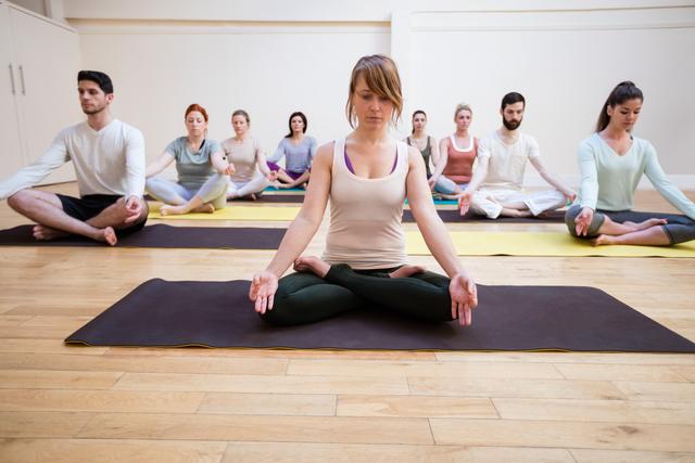 Trainer assisting group of people with lotus position - Download Free Stock Photos Pikwizard.com