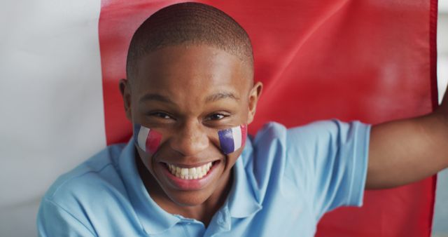 Image of happy african american boy with flag of france cheering. Cheering, sport, soccer fan and patriotism concept.