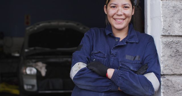 Portrait of female mechanic with arms crossed smiling at a car service station. automobile repair service