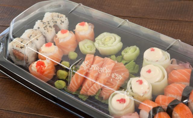 Set of assorted sushi kept in a plastic box on wooden table - Download Free Stock Photos Pikwizard.com