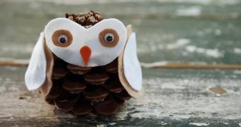 A handmade owl crafted from a pinecone and felt materials sits on a ...