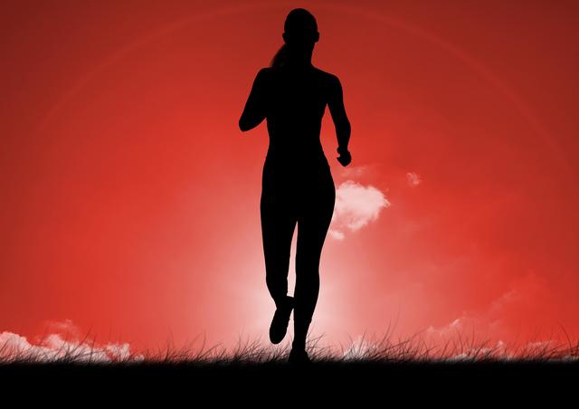 Silhouette of woman running on grass against red background