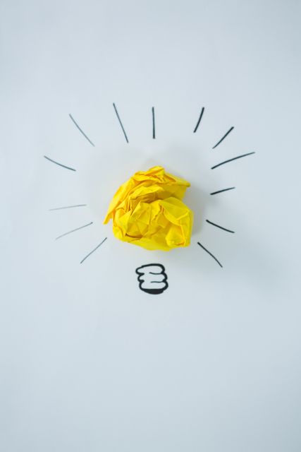 Conceptual image of light bulb drawn around crumbled yellow paper