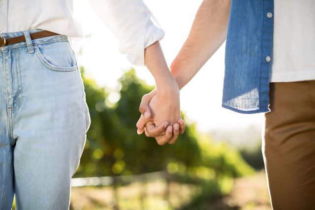 Mid section of couple holding hands on sunny day