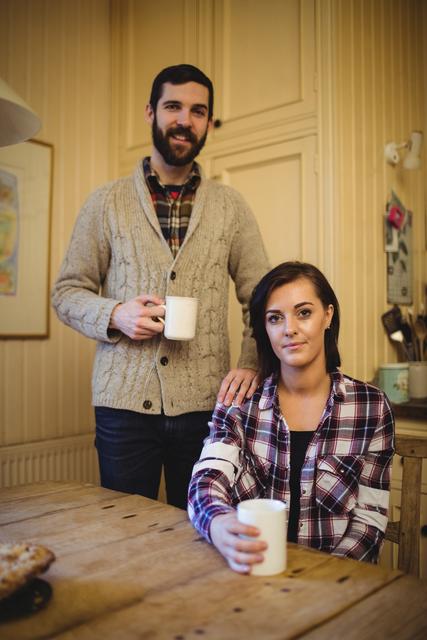 Couple holding mug of coffee at home