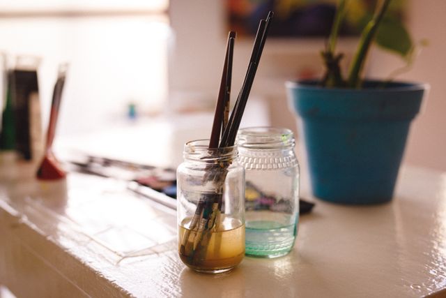 Dirty brushes in jar lying on desk in art studio - Download Free Stock Photos Pikwizard.com