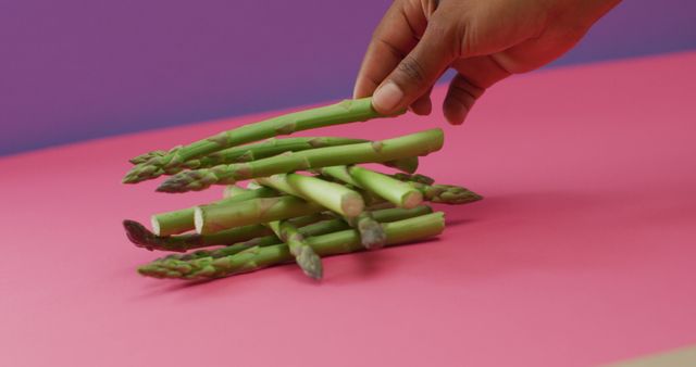 Image of biracial woman arranging fresh asparagus stalks over pink and purple background - Download Free Stock Photos Pikwizard.com