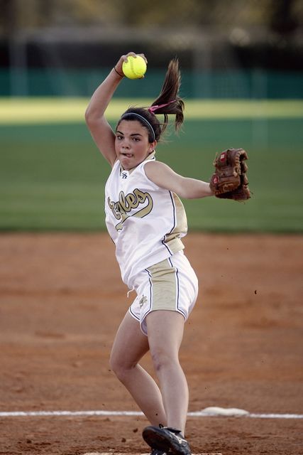 Caucasian female pitcher throwing a ball while playing softball. Sports and fitness concept