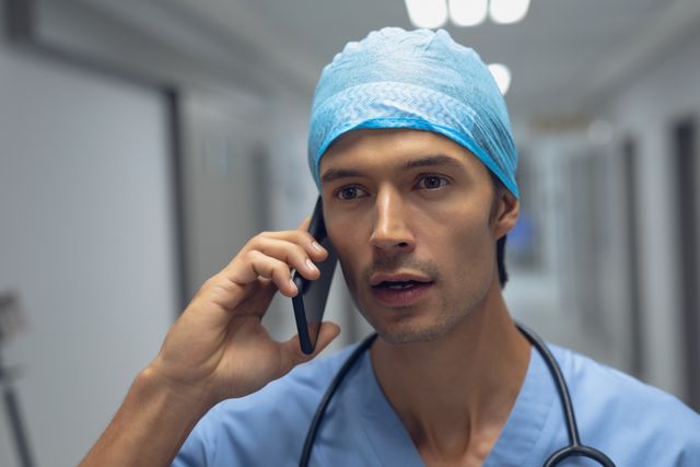 Male surgeon talking on mobile phone in the corridor at hospital