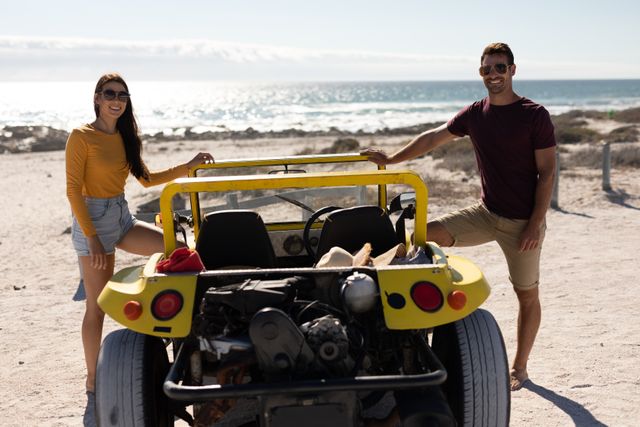 Portrait of happy caucasian couple standing by beach buggy on sunny beach by the sea - Download Free Stock Photos Pikwizard.com