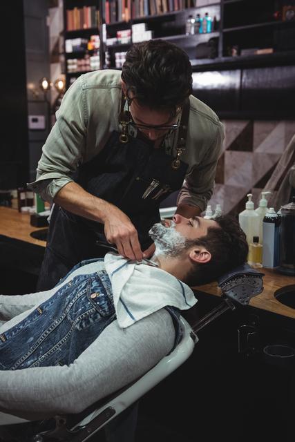 Man getting his beard shaved with razor in barber shop