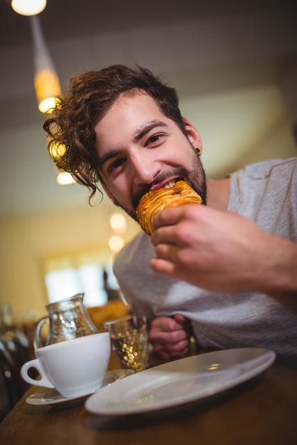 Man eating a croissant in cafÃ© - Download Free Stock Photos Pikwizard.com