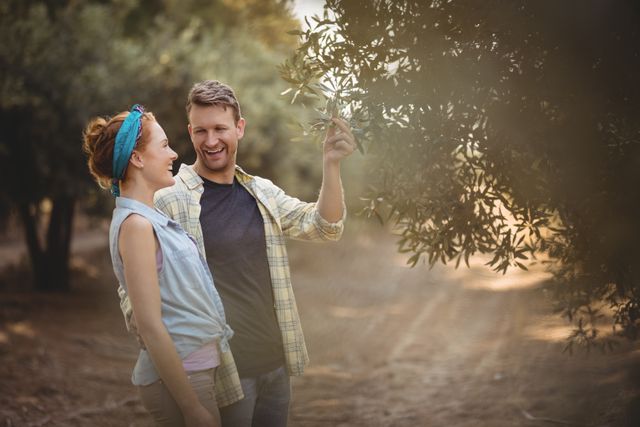 Young couple standing by olive tree at farm - Download Free Stock Photos Pikwizard.com