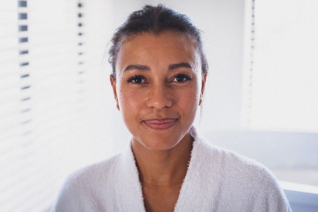 Portrait of mixed race woman wearing bathrobe looking to camera and smiling - Download Free Stock Photos Pikwizard.com